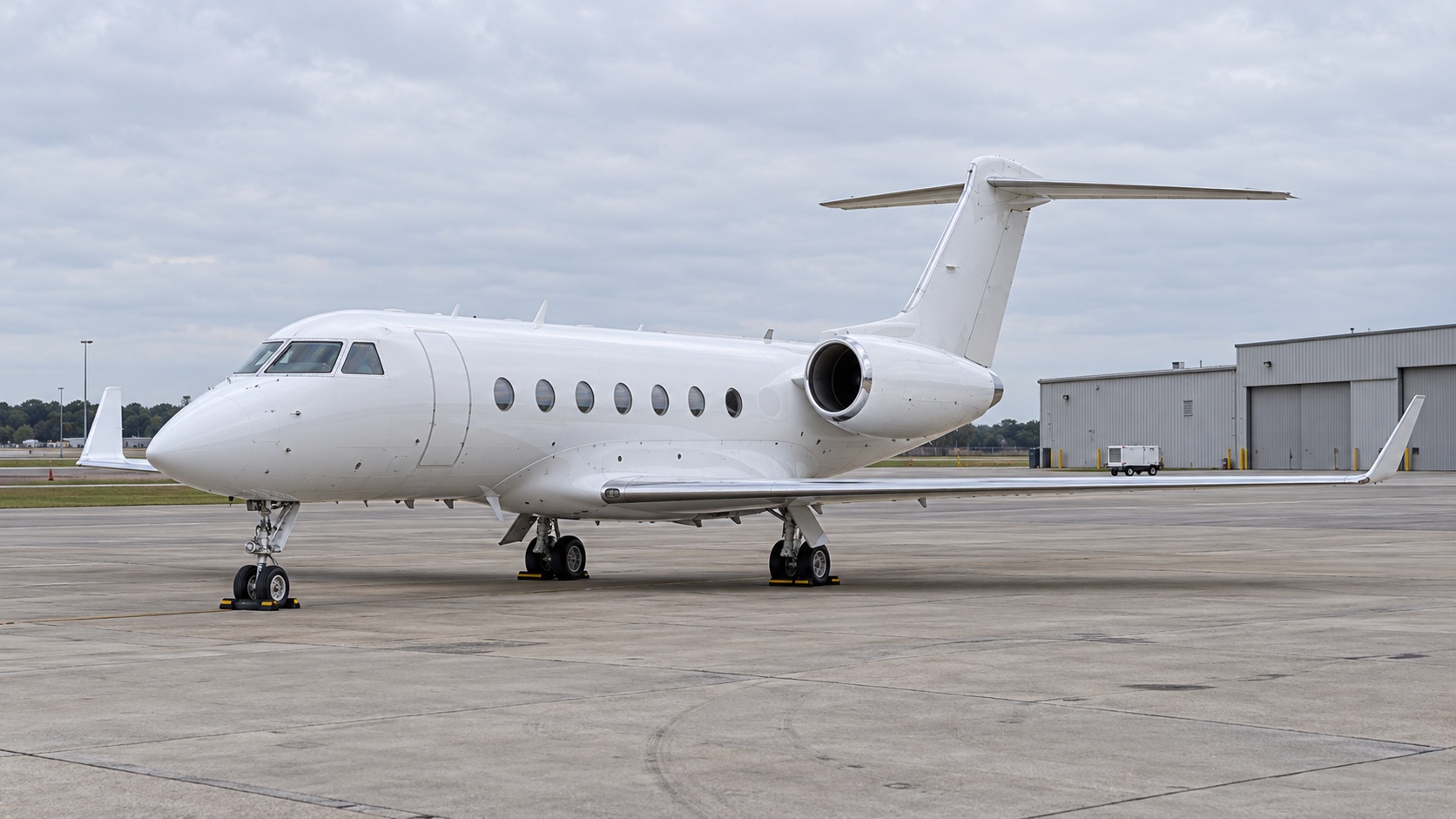 An all-white private aircraft parked on an airport apron in daylight